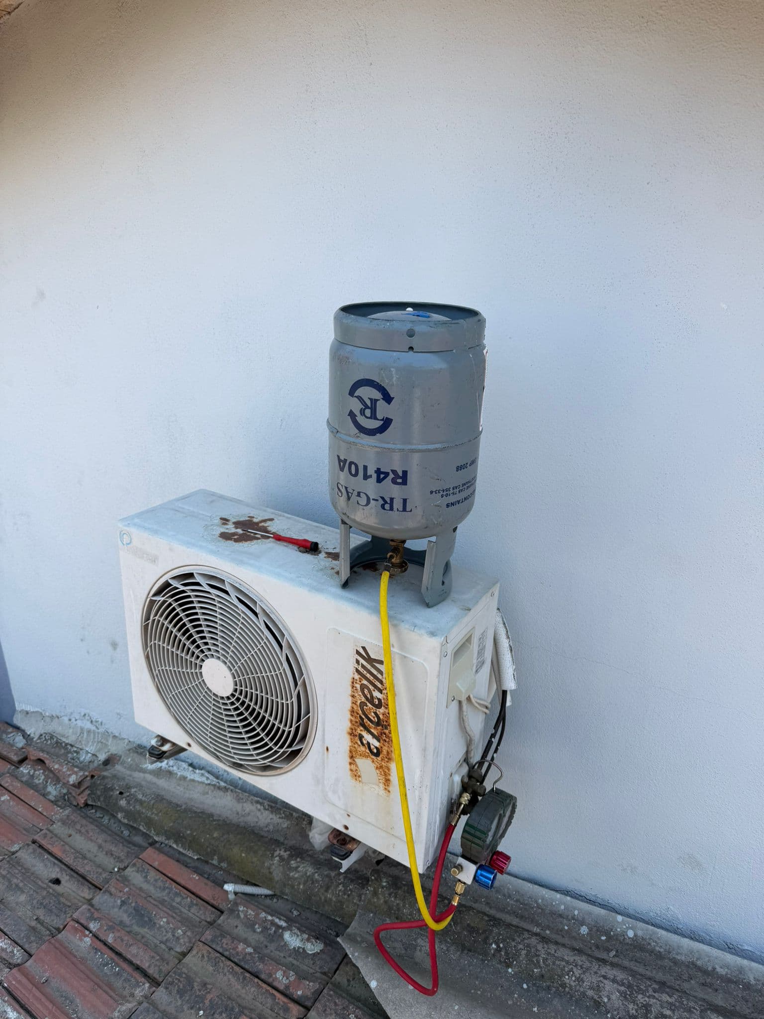 Arçelik dış ünitenin üzerine ters yerleştirilmiş R410A soğutucu gaz tüpü; sarı şarj hortumu tüpten aşağı inerek servis vanasındaki manometre setine bağlanıyor